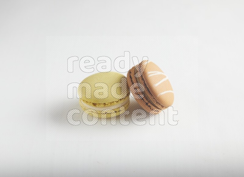 45º Shot of of two assorted Brown Irish Cream, and Yellow Lime macarons on white background