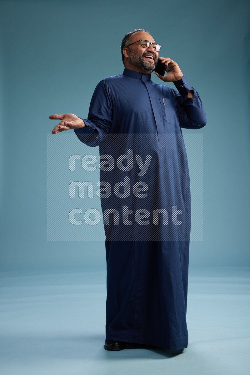 Saudi Man without shimag Standing talking on phone on blue background