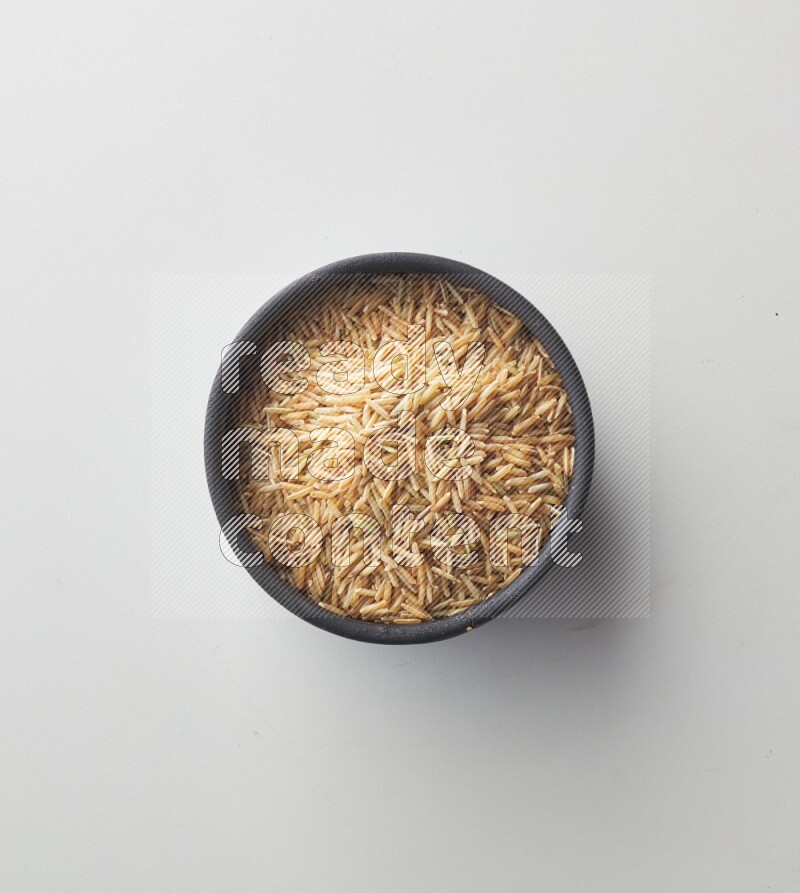 Top-view shot of long grain brown rice in a container on white background