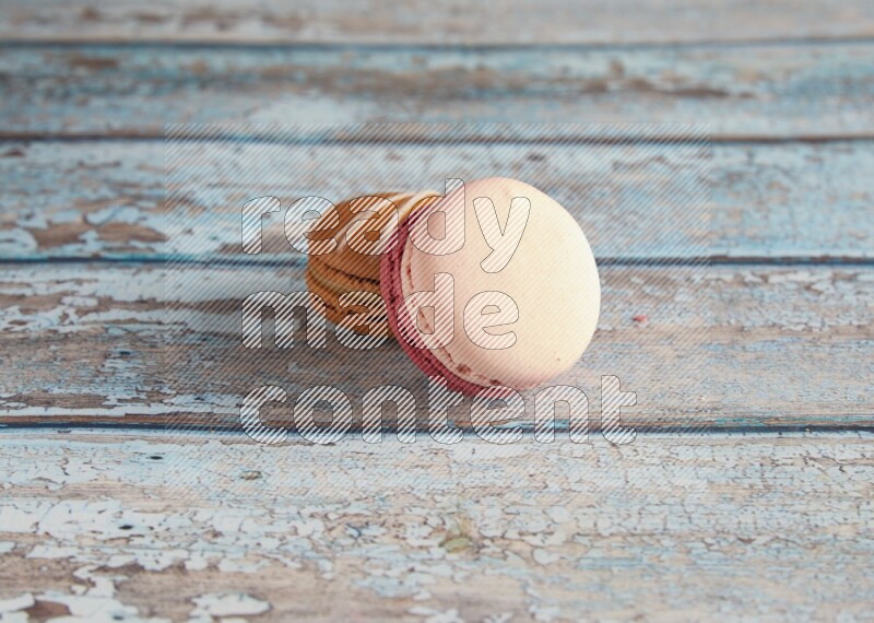 45º Shot of of two assorted Brown Irish Cream, and Pink Litchi Raspberry macarons on light blue background