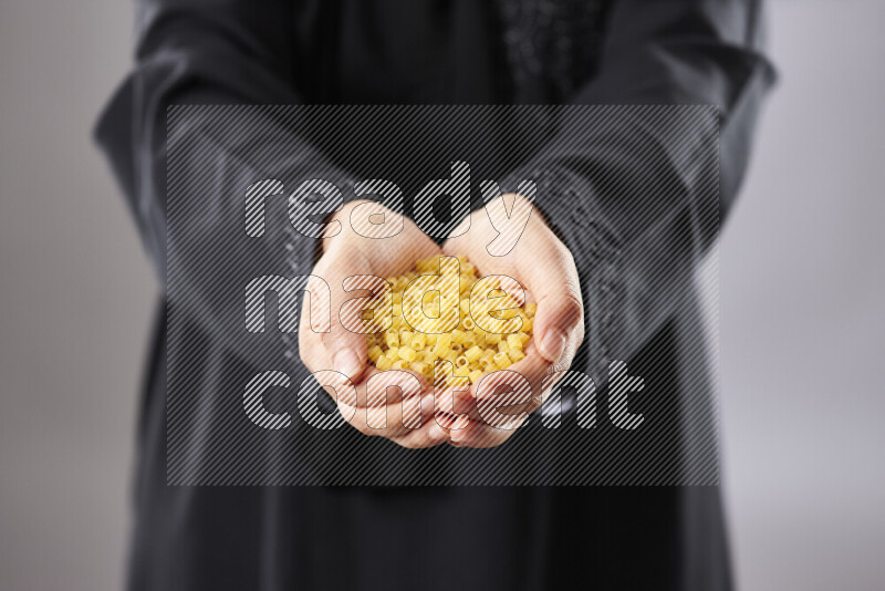 Woman in abaya holding different kinds of pasta in different positions