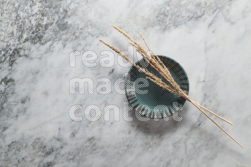 Wheat stalks on multicolored pottery plate on grey marble background