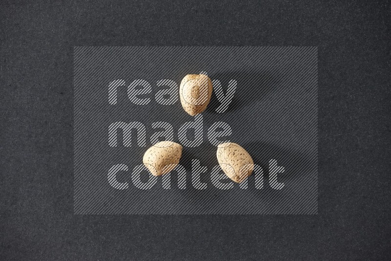 3 almonds on a black background in different angles