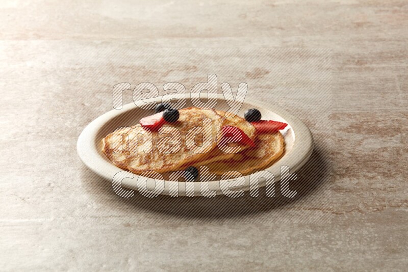 Three stacked mixed berries pancakes in a beige plate on beige background
