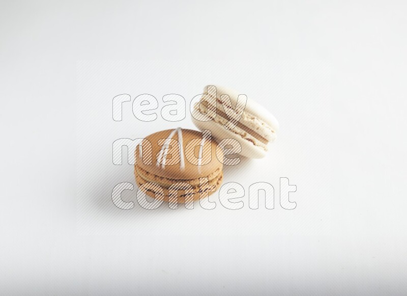 45º Shot of of two assorted Brown Irish Cream, and White Caramel fleur de sel macarons on white background