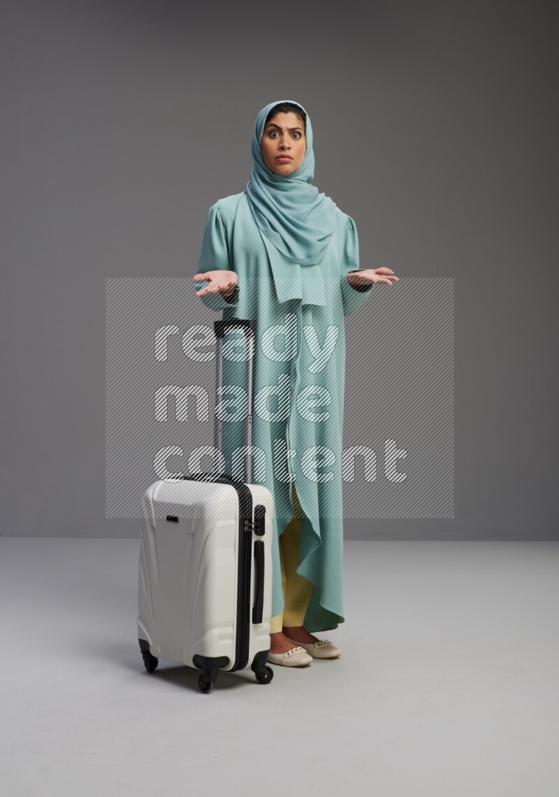 Saudi Woman wearing Abaya standing holding Travel bag on Gray background