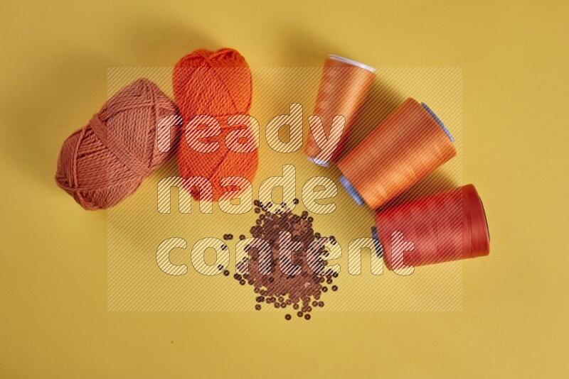 An orange collection of sewing and tailoring tools arranged on a yellow background