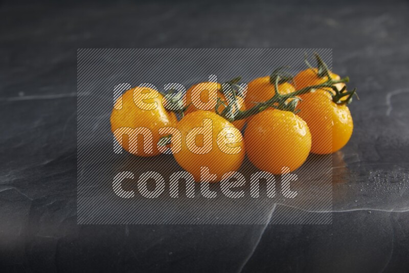 Yellow cherry tomato vein on a textured black slate background 45 degree