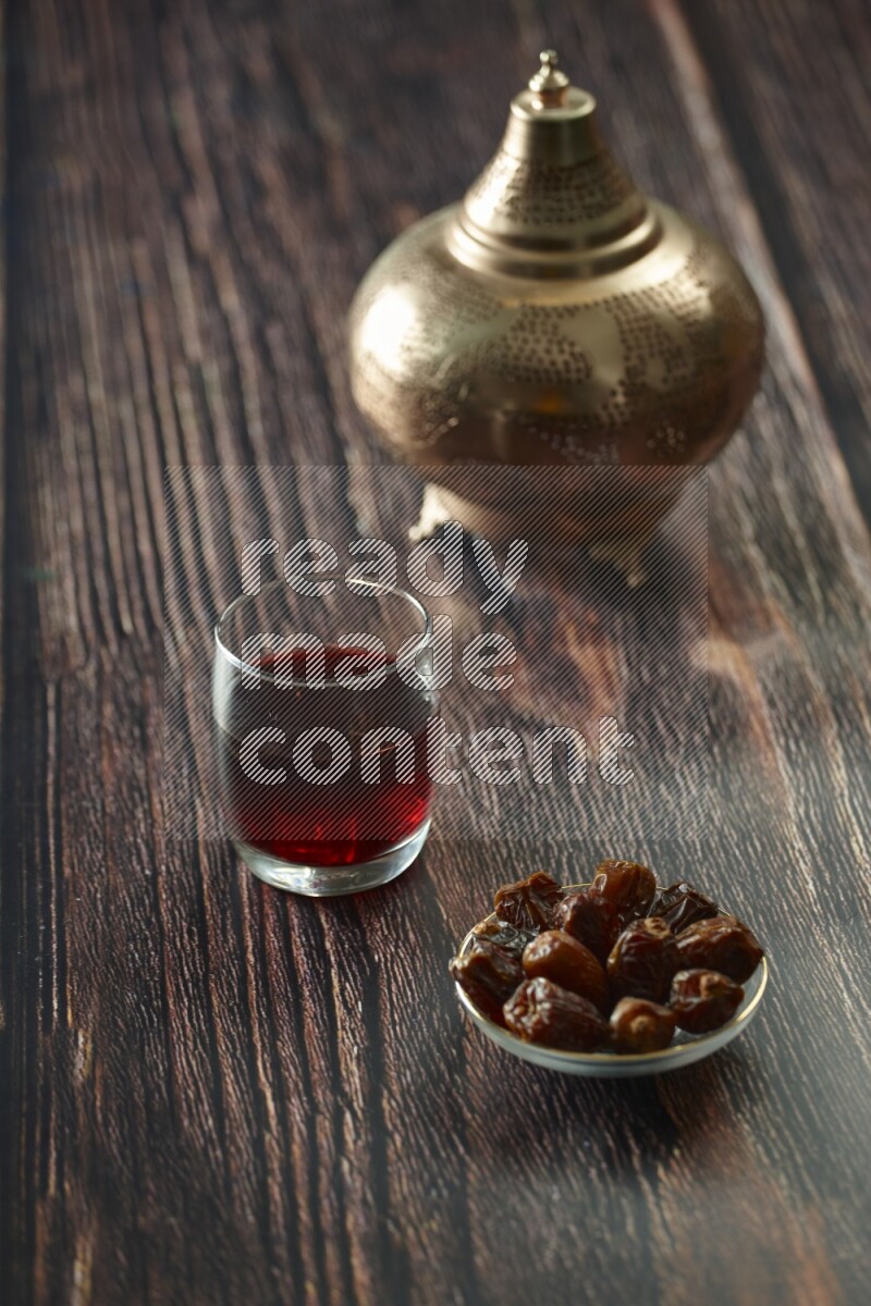 A golden lantern with different drinks, dates, nuts, prayer beads and quran on brown wooden background