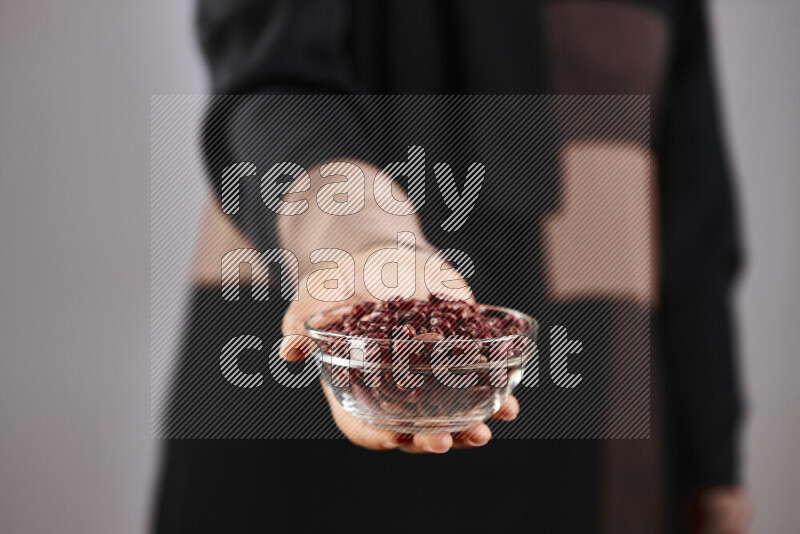 Woman in abaya holding different kinds of legumes in different positions