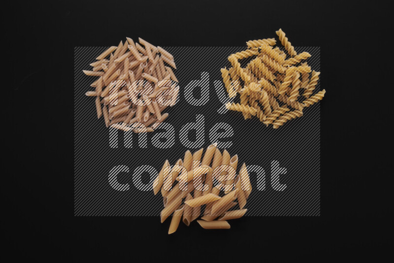 Different pasta types in bunches on black background