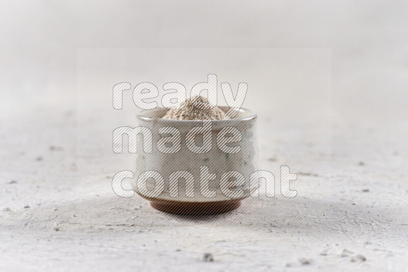 A beige pottery bowl full of onion powder on white background