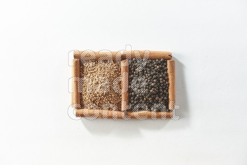 2 squares of cinnamon sticks full of mustard seeds and black peppers on white flooring