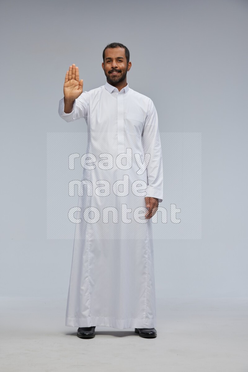 Saudi man Wearing Thob standing interacting with the camera on Gray background