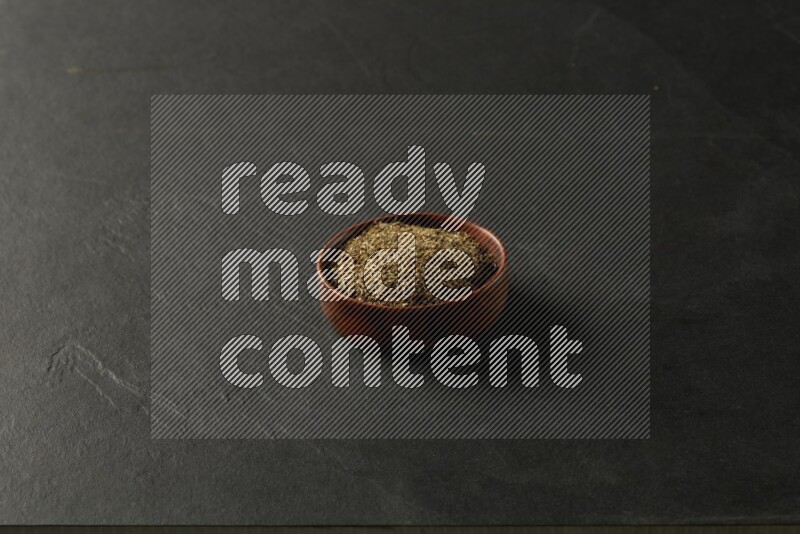 wooden round sauce bowl filled with herbs on grey textured countertop