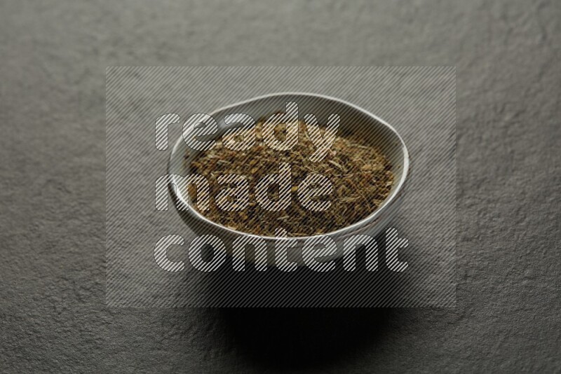 multi color round sauce bowl filled with herbs on grey textured countertop