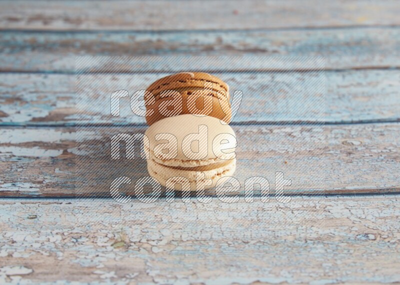 45º Shot of of two assorted Brown Irish Cream, and White Caramel fleur de sel macarons on light blue background