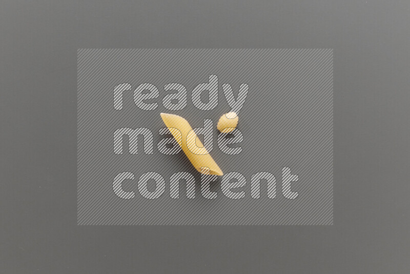 Penne pasta with other types of pasta on grey background
