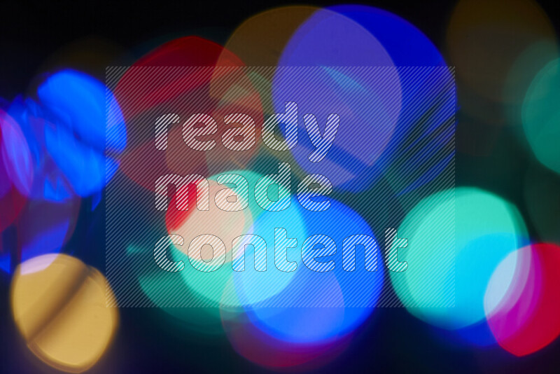 Light bulbs glowing against backdrop of multicolord bokeh