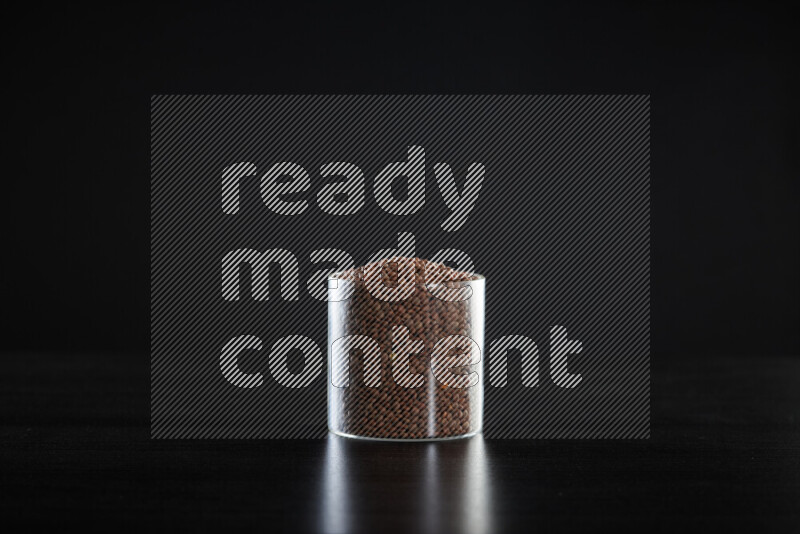 Brown lentils in a glass jar on black background