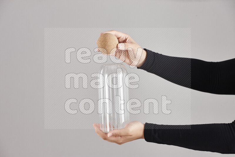 A woman in black abaya holding different glassware in different positions