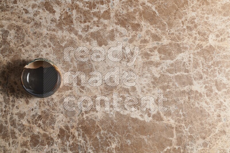 A multicolored pottery bowl on beige marble background