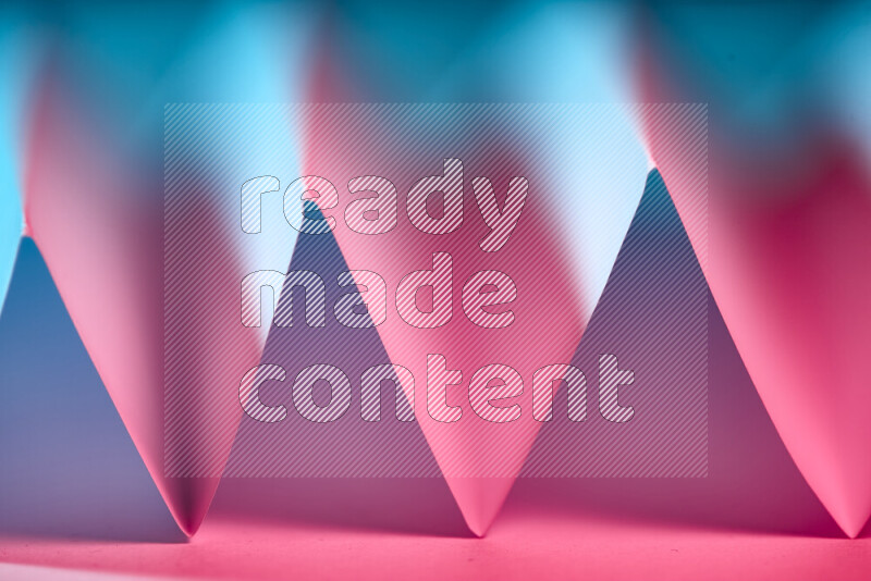 صورة مجردة مقربة تظهر طيات ورقية هندسية حادة بتدرجات اللون الأزرق والأحمر