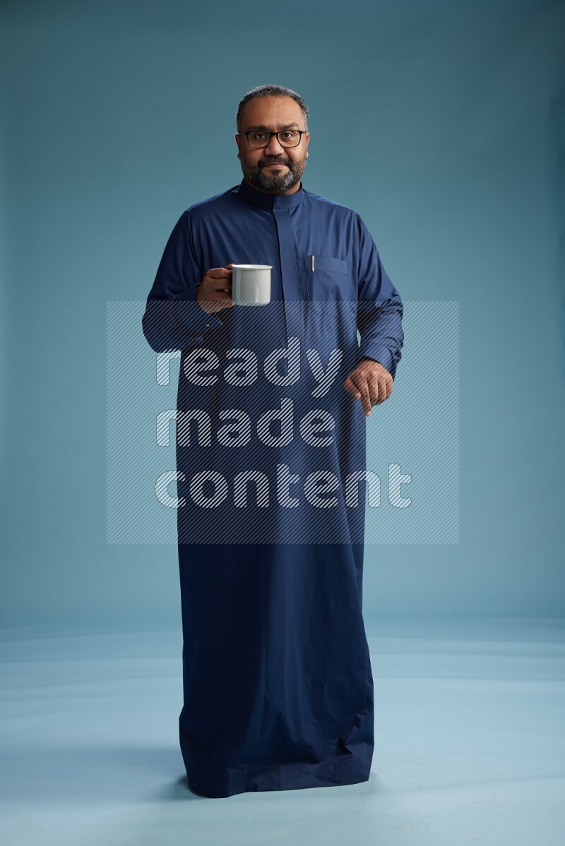 Saudi Man without shimag Standing drinking coffee on blue background