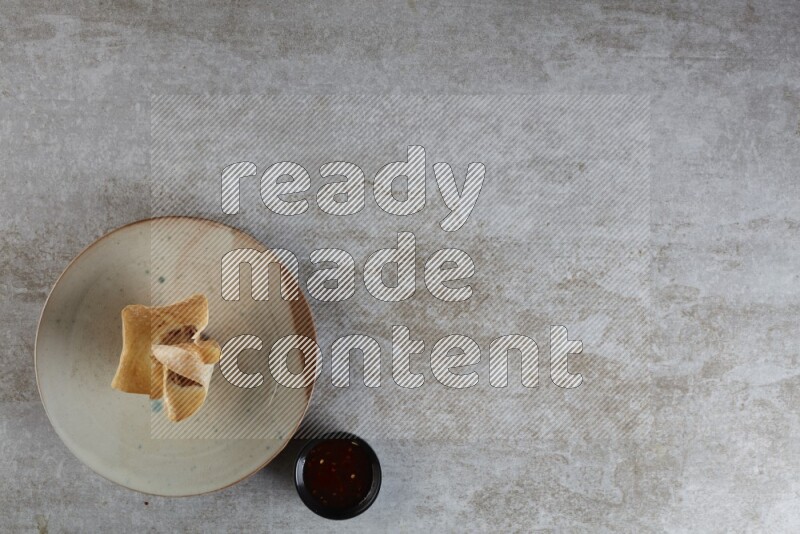 wonton cups with soy sauce ramkin on multi colored pottery on grey textured counter top
