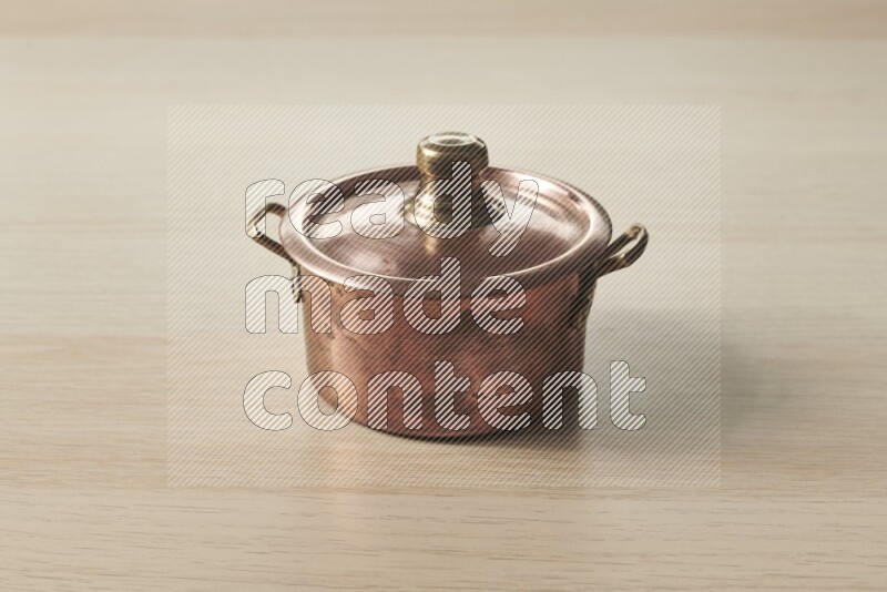 A small copper pot on light wooden background