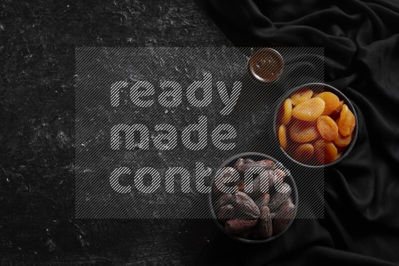 Dried fruits in pottery bowls with coffee in a dark setup