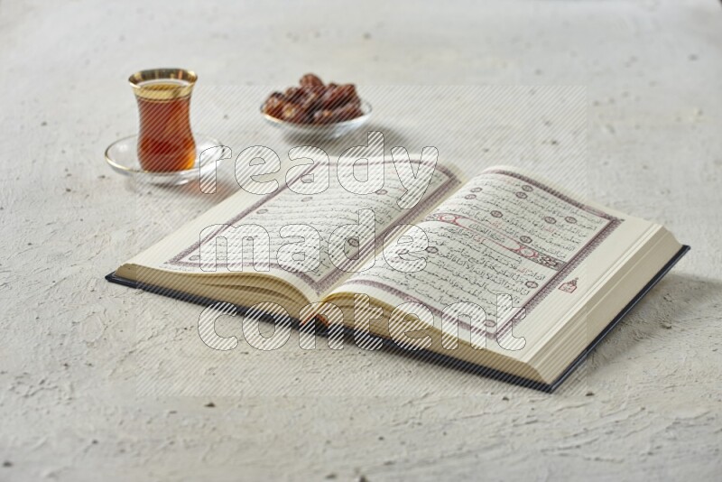 Quran with dates, prayer beads and different drinks all placed on textured white background