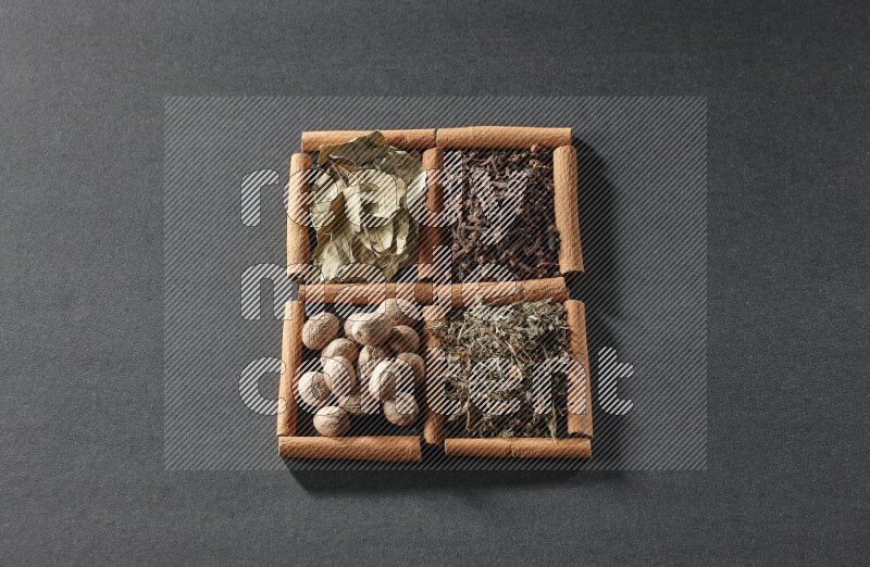 4 squares of cinnamon sticks full of bay laurel leaves, dried basil, cloves and nutmegs on black flooring