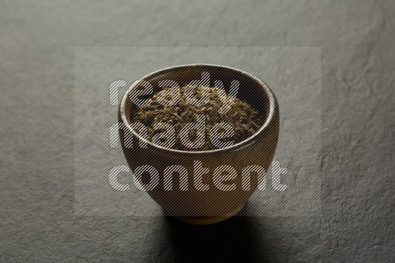 wooden round sauce bowl filled with herbs on grey textured countertop