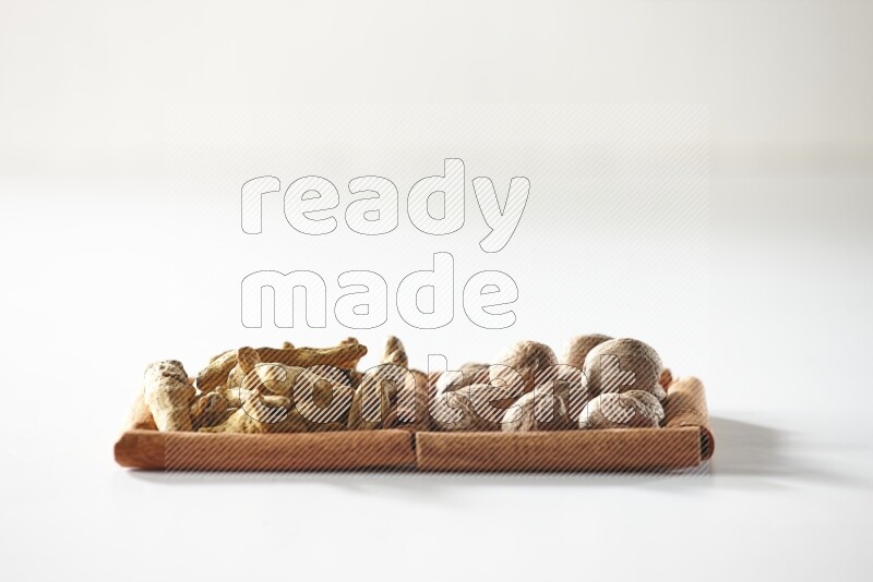 2 squares of cinnamon sticks full of turmeric fingers and nutmegs on white flooring