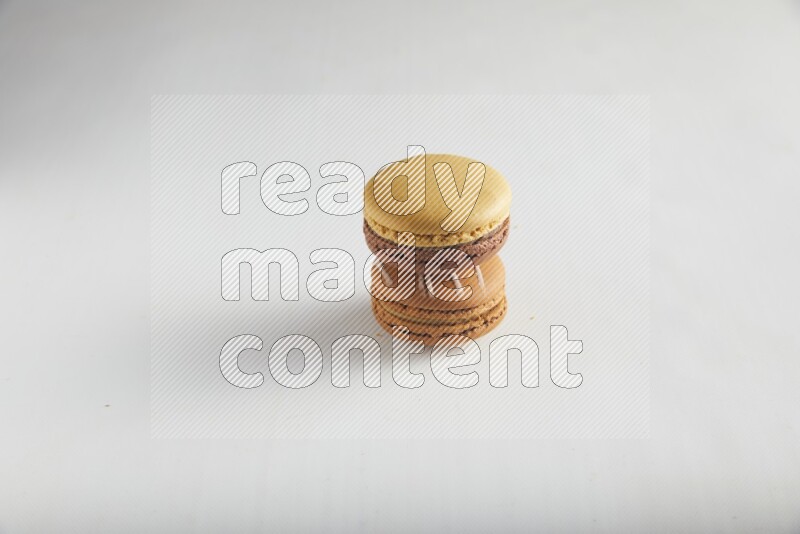 45º Shot of of two assorted Brown Irish Cream, and Yellow, and Brown Chai Latte macarons on white background