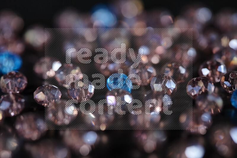 Rose and blue transparent crystal beads scattered on a black background