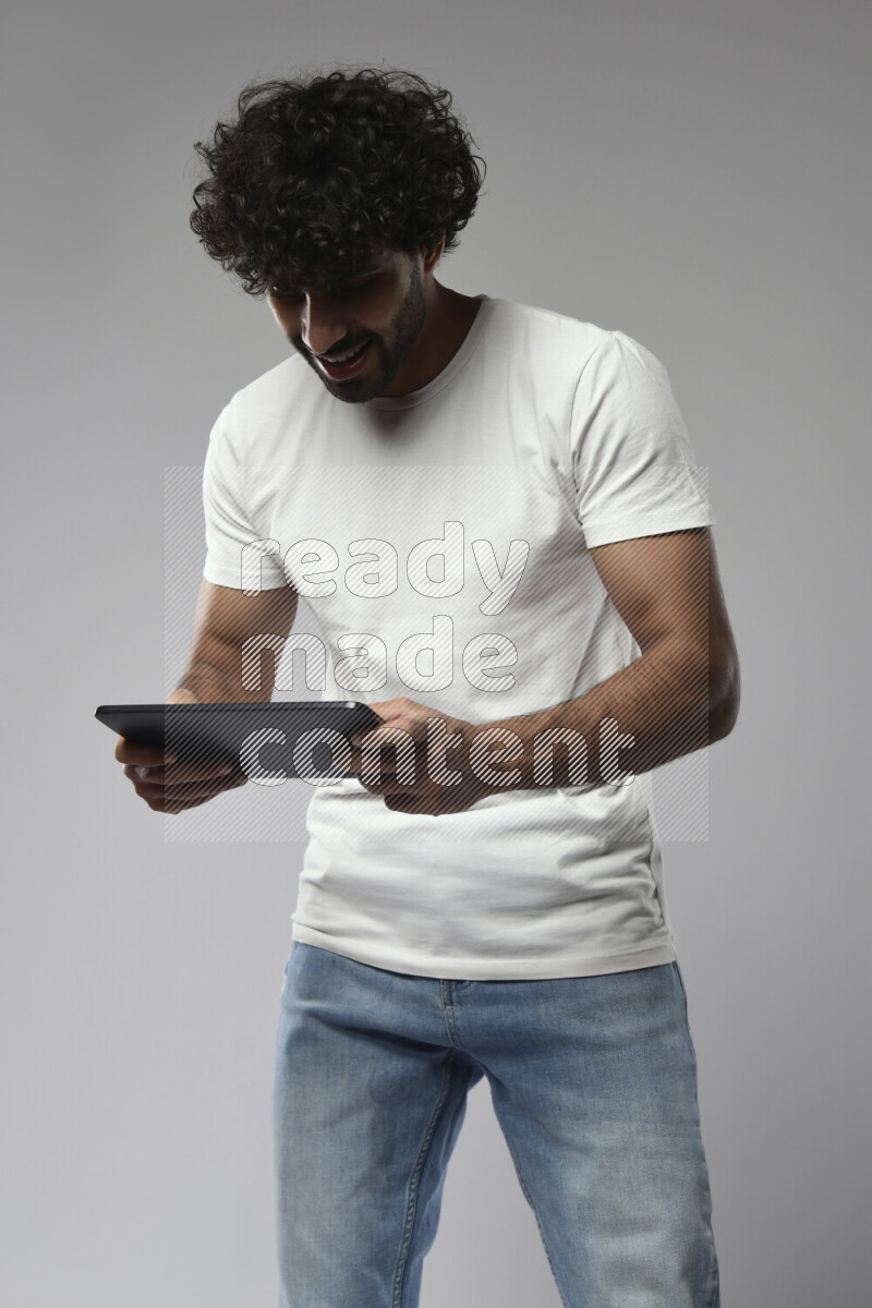 A man wearing casual standing and gaming on a tablet on white background