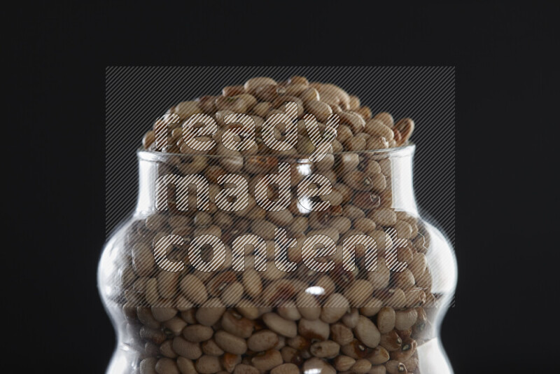 Black-eyed peas in a glass jar on black background