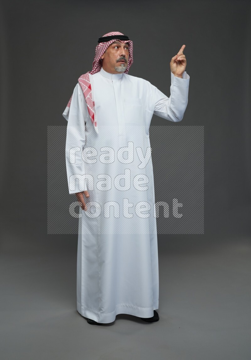 Saudi man with shomag Standing Interacting with the camera on gray background