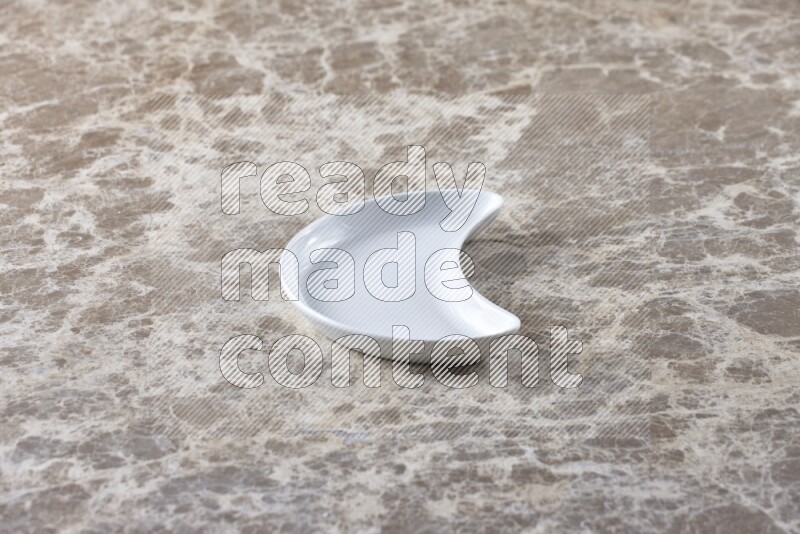 A pottery crescent plate on beige marble background