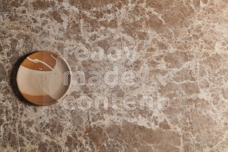 A multicolored pottery plate on beige marble background