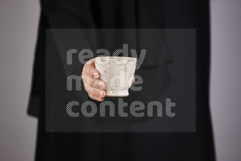 A woman in black abaya holding different pottery essentials in different positions