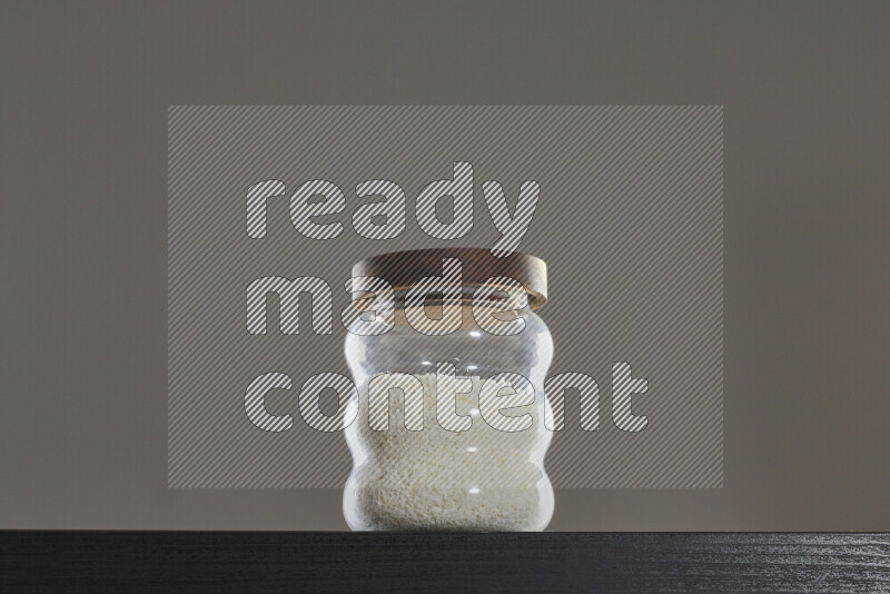 Desiccated coconut in a glass jar on black background