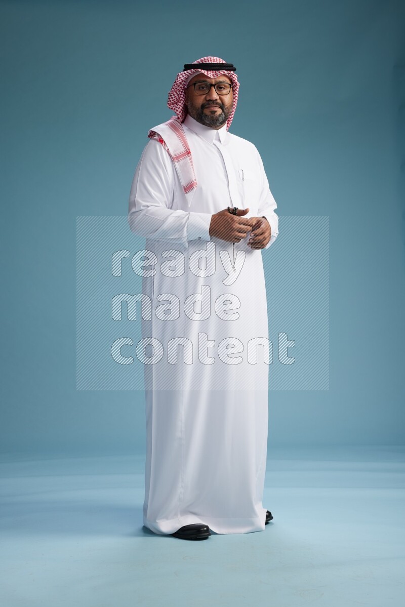 Saudi Man with shimag Standing Interacting with the camera on blue background