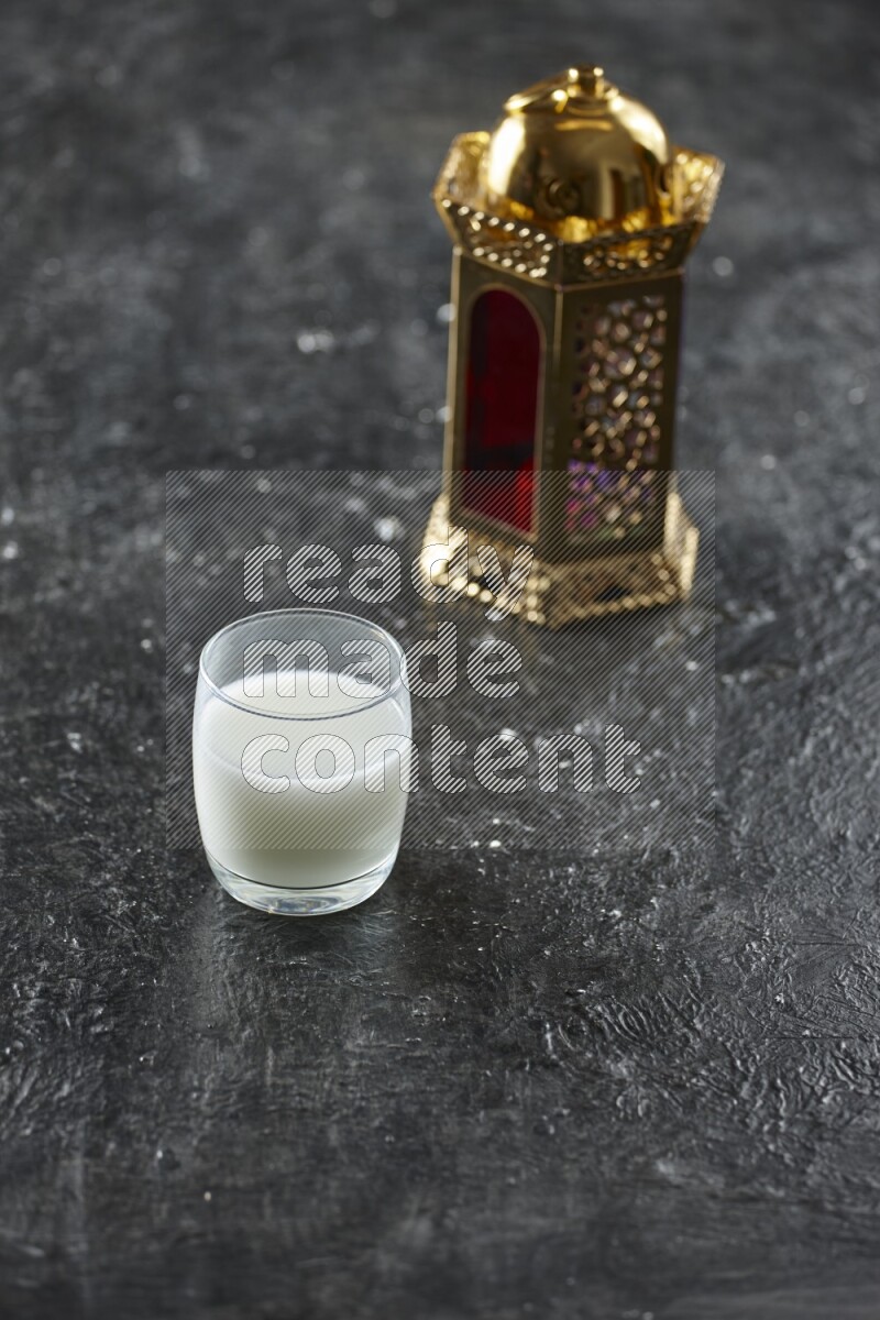A golden lantern with different drinks, dates, nuts, prayer beads and quran on textured black background