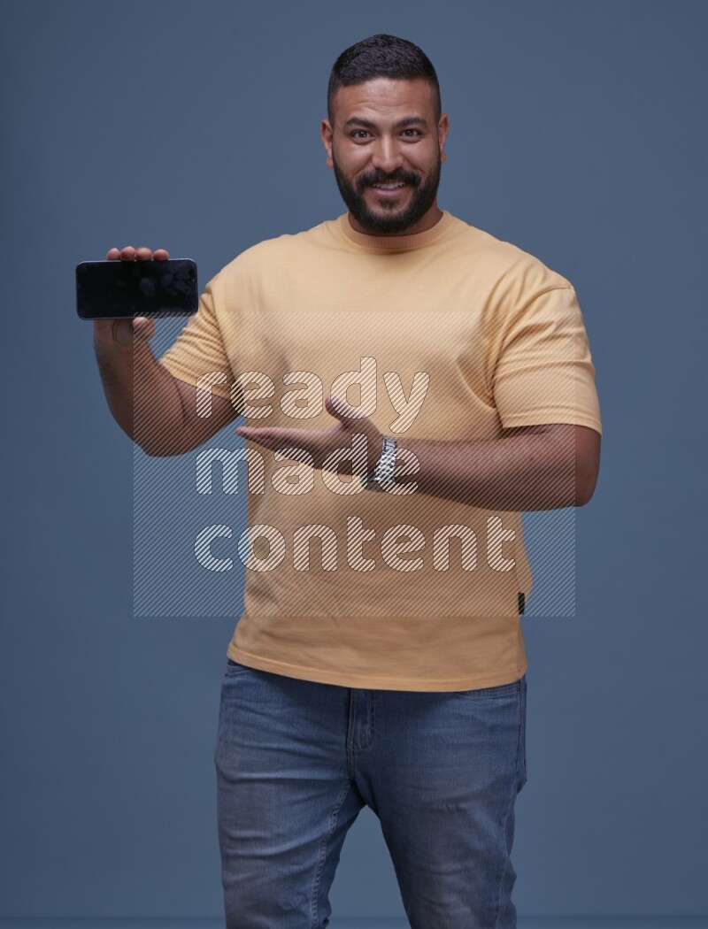 A man Showing His Smart Phone on Blue Background wearing Orange T-shirt