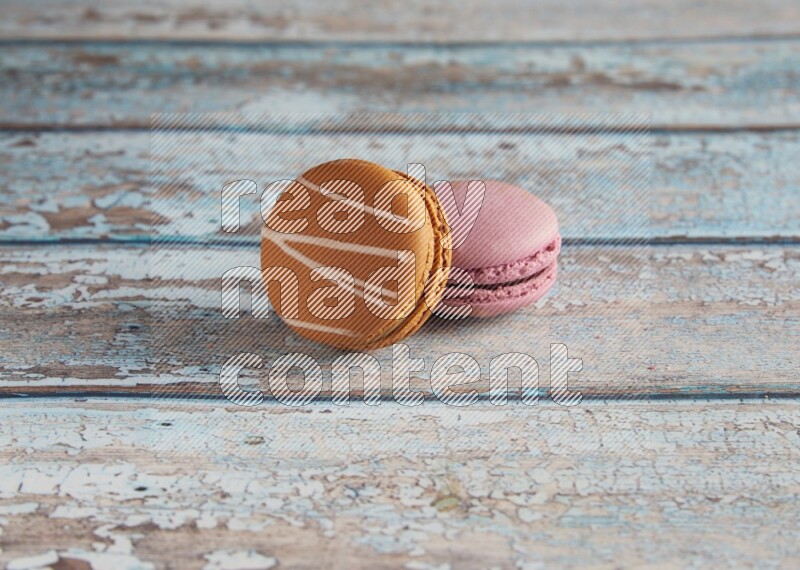 45º Shot of of two assorted Brown Irish Cream, and Purple Strawberry macarons  on light blue background