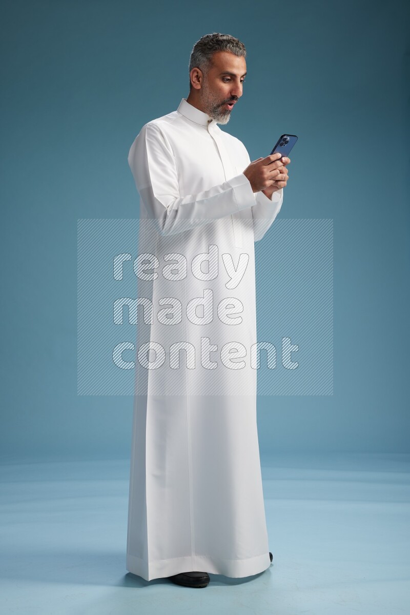 Saudi man waring thob texting on blue background