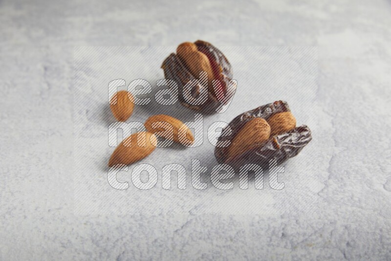 two almond stuffed madjoul dates on a light grey background